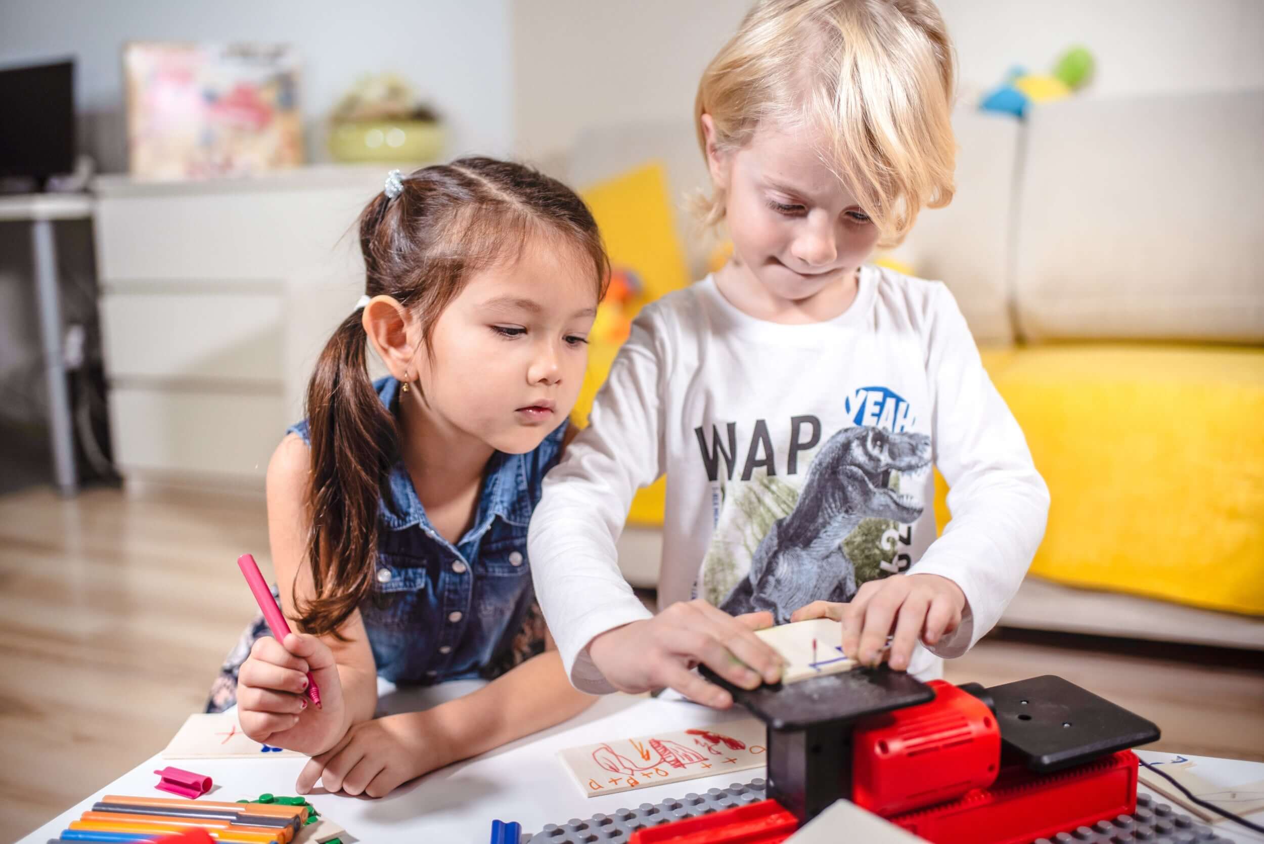 Zwei Kinder arbeiten an einem Tisch mit PLAYmake und einer Holzplatte.